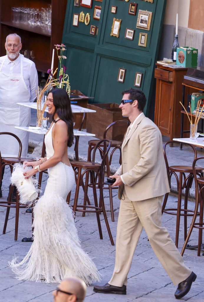 Photo © 2026 Backgrid UK/The Grosby Group

PREMIUM EXCLUSIVE
Palermo, Sicily, June 5, 2026.

Dua Lipa and her husband Callum Turner were seen arriving at Palazzo Gangi in Palermo, Sicily, for their pre-wedding party celebrations. The singer wore a striking white textured gown featuring a fitted silhouette, open-back design and feathered detailing at the hem, paired with a matching feather-trimmed handbag. Turner opted for a light beige suit and sunglasses as the couple arrived smiling ahead of the festivities.
***
Dua Lipa y su esposo Callum Turner fueron vistos llegando al Palazzo Gangi en Palermo, Sicilia, para la fiesta previa a su boda. La cantante lució un llamativo vestido blanco texturizado de silueta ajustada, espalda descubierta y detalles de plumas en el bajo, combinado con un bolso a juego adornado con plumas. Turner eligió un traje beige claro y gafas de sol mientras la pareja llegaba sonriente a las celebraciones.