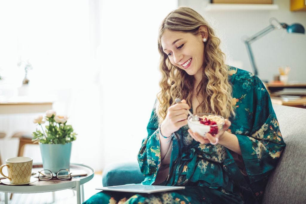 mujer comiendo comida sana mientras mira su tablet