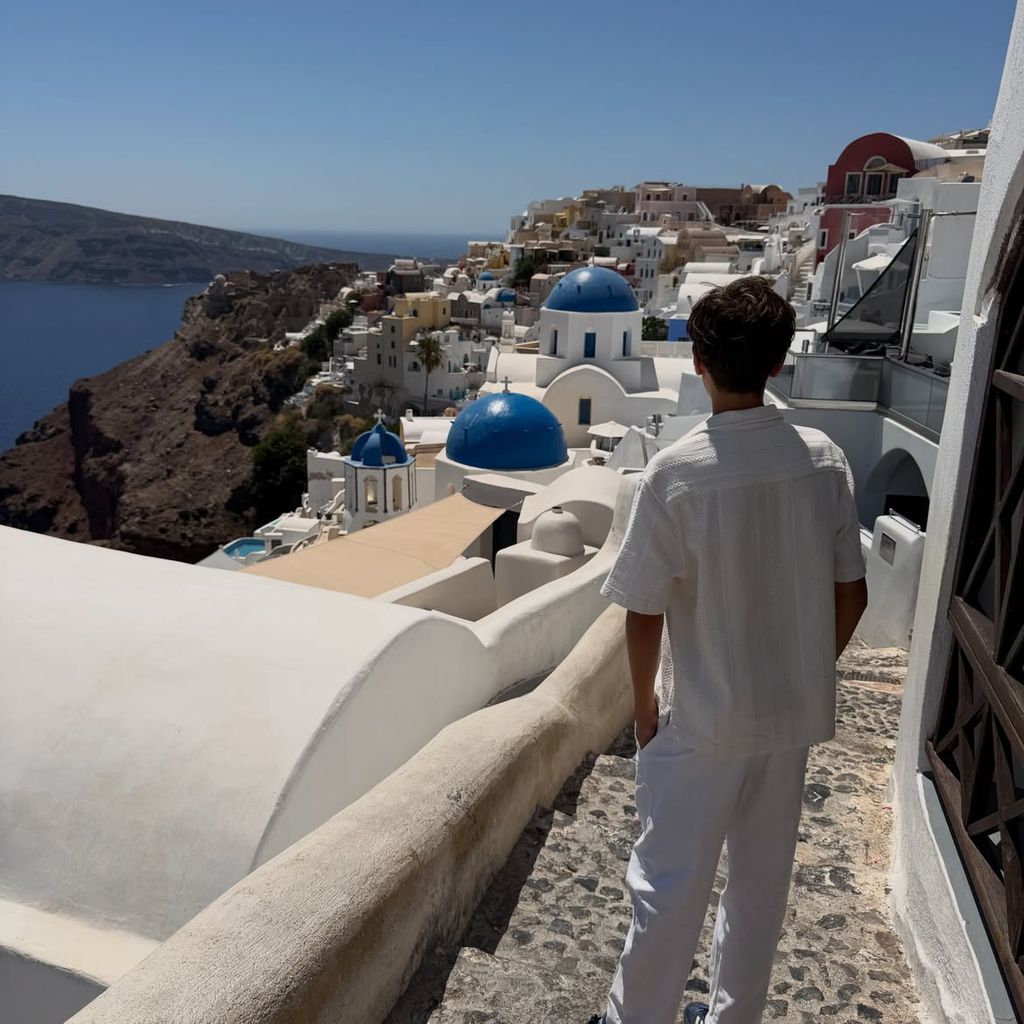 Lucas pasea por las calles de Santorini con un conjunto blanco formado por camisa y pantalón de lino