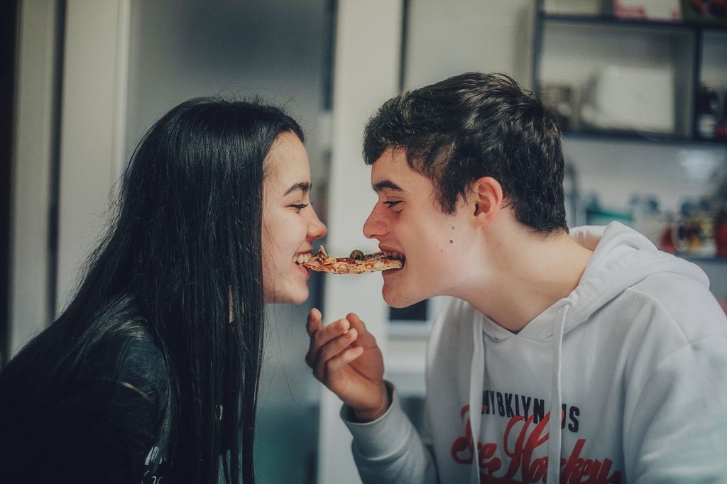 pareja de adolescentes compartiendo un trozo de pizza