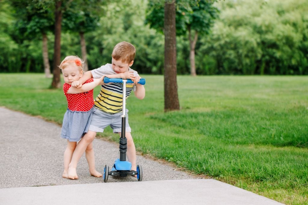 Hermanos pelelándose por un patinete