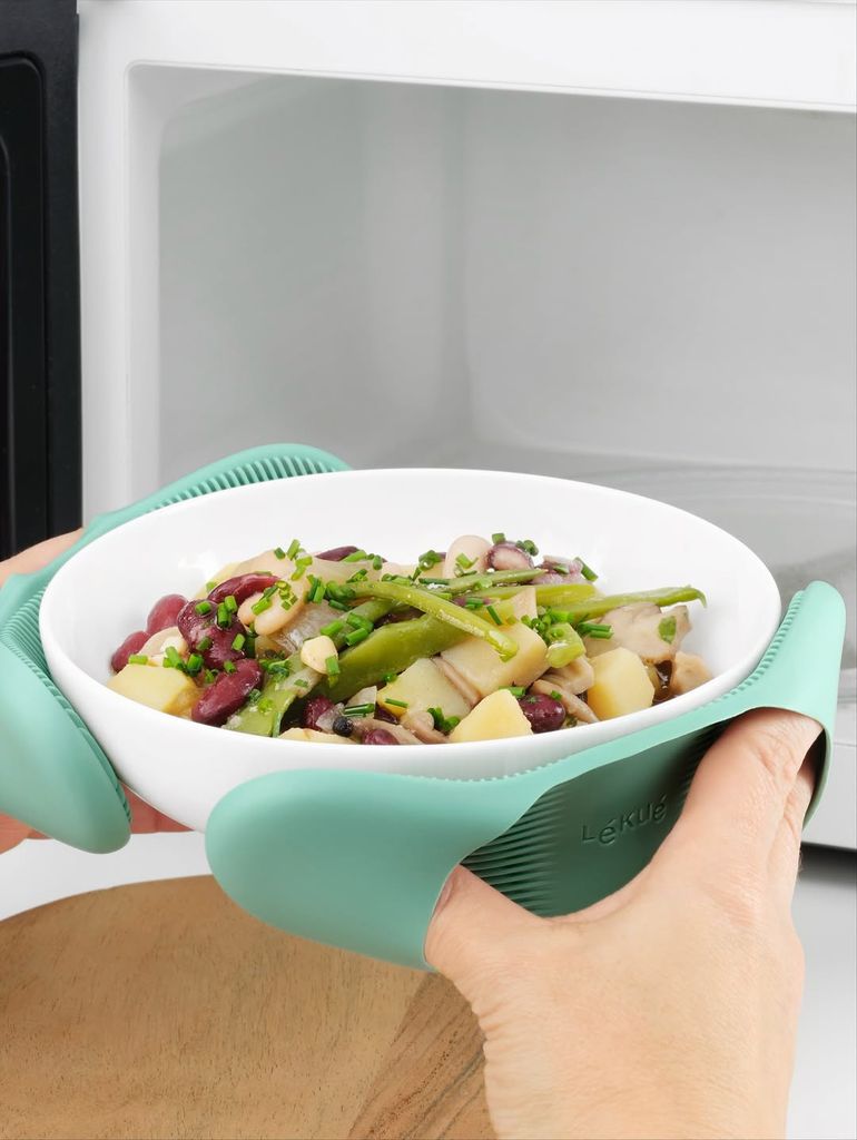 Una mujer metiendo un plato de verduras en el microondas