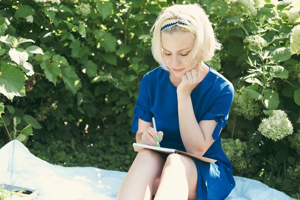 Mujer rubia escribiendo un diario con expresión serena