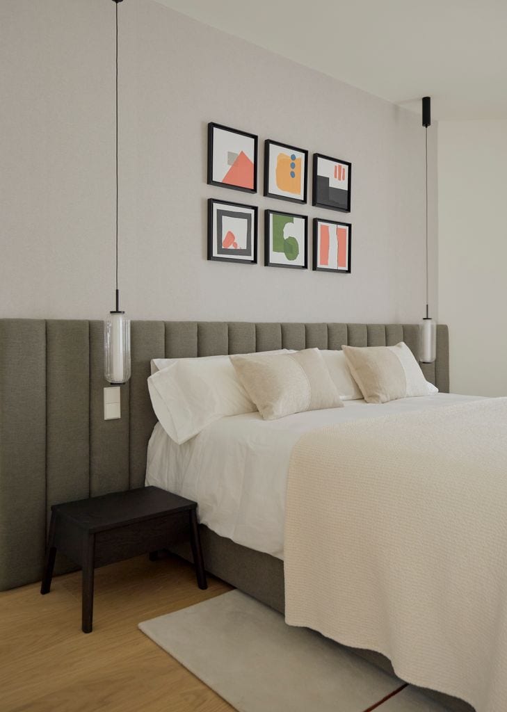 Dormitorio con cabecero tapizado y composición de láminas