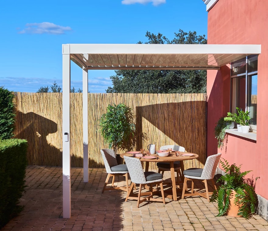Jardín con pérgola bioclimática adosada en la pared.