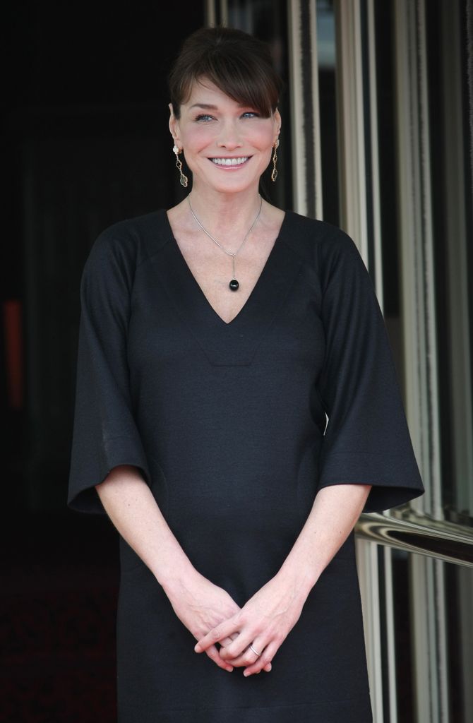 Plano medio de Carla Bruni con vestido negro durante un evento oficial