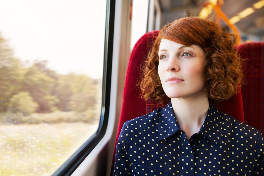 Mujer mirando por la ventana mientras viaja en tren