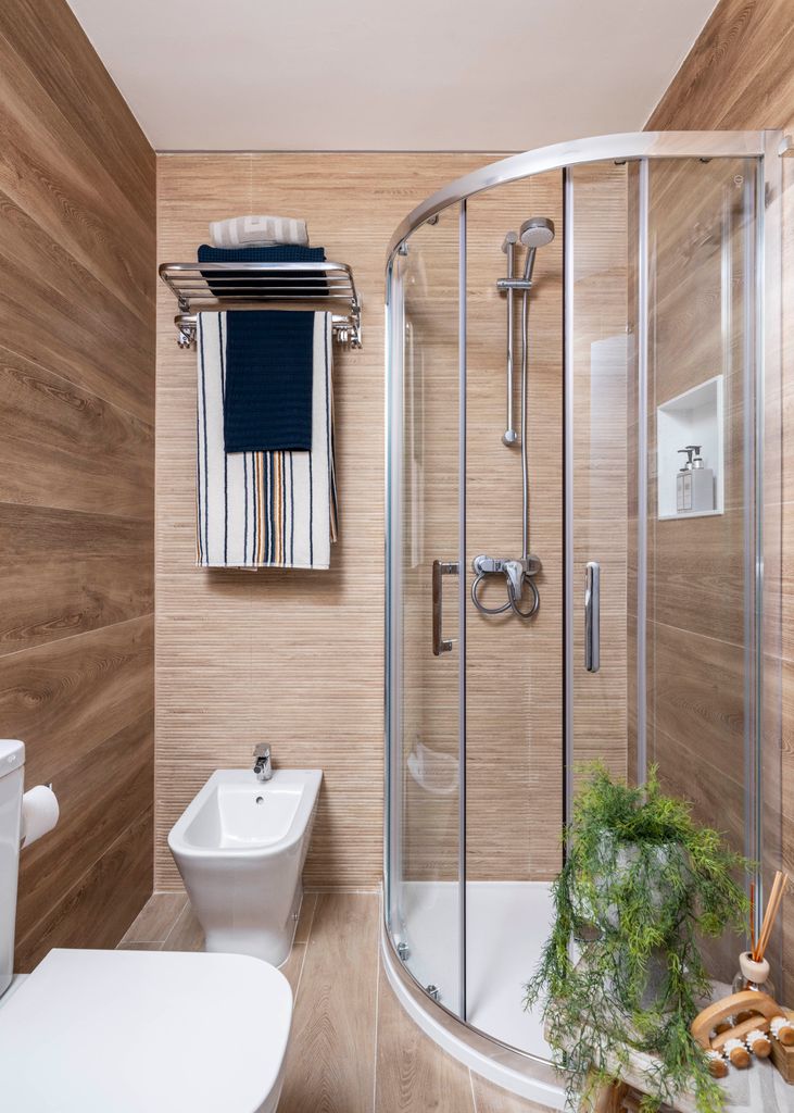 Baño pequeño con estantería encima del inodoro. 