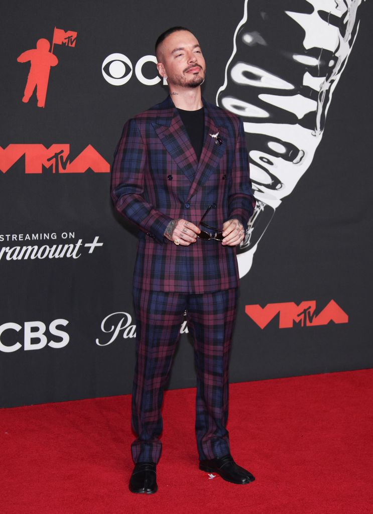 J Balvin camina la alfombra en un traje cruzado en estampado plaid y zapatos tabi.  