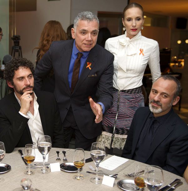 Paco León en traje y Juan Ramón Lucas en traje, junto a otros en una cena formal.