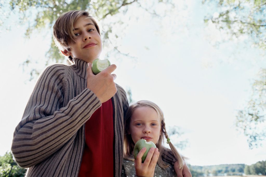 hermano mayor con su hermana pequeña comiendo una manzana