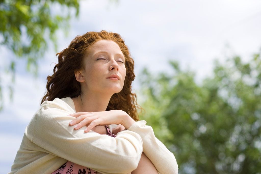 Mujer pelirroja con los ojos cerrados y respirando