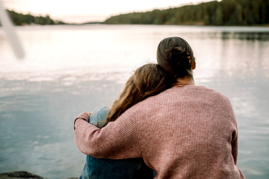 Madre abrazando a su hija en un lago