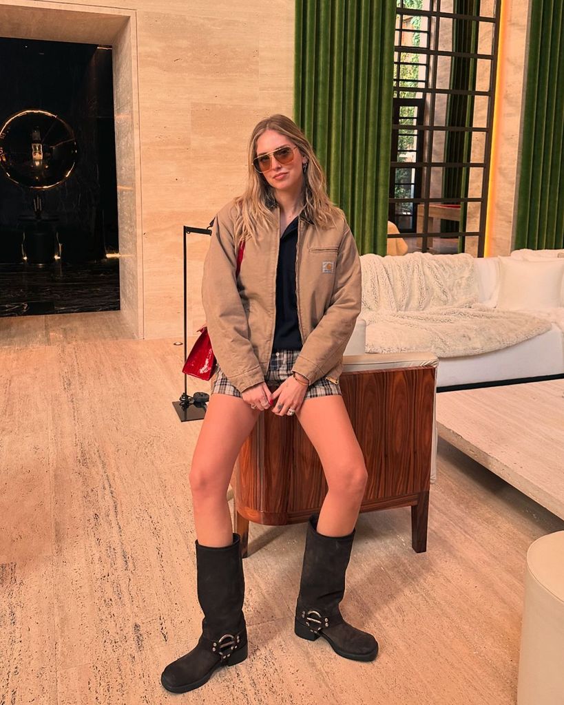 Plano entero de Chiara Ferragni con chaqueta marrón y botas negras altas