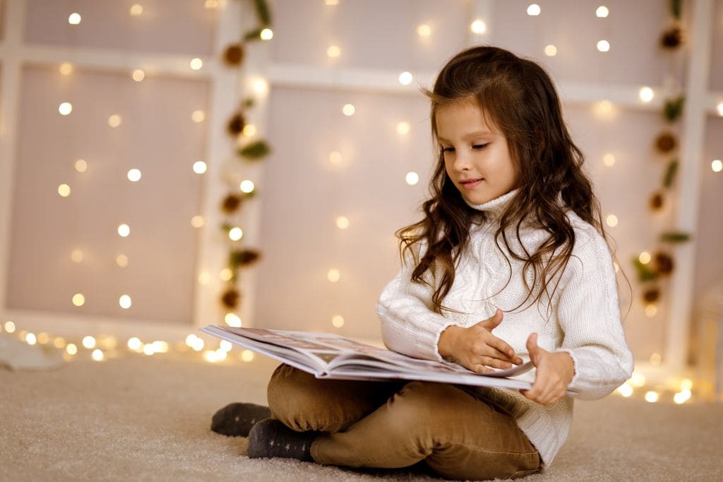 Niña leyendo un libro en Navidad