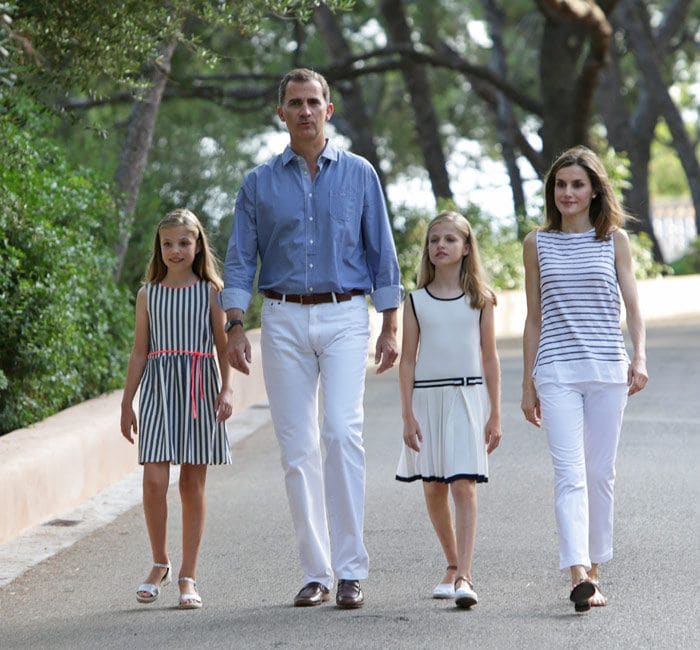 No han ido vestidos iguales pero si han respetado los cuatro los colores 'oficiales' para estas fotos de verano: blanco y azul. Felipe VI llevaba camisa en azulón y pantalón blanco mientras que la Reina y sus hijas han jugado con el blanco y rayas azul marino: horizontales en el caso de doña Letizia, verticales en el vestido de Sofía y adornando en ribetes el vestido de la Princesa de Asturias
