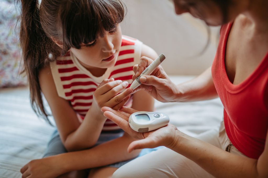niña con diabetes y su madre, midiendo los niveles de glucosa en sangre