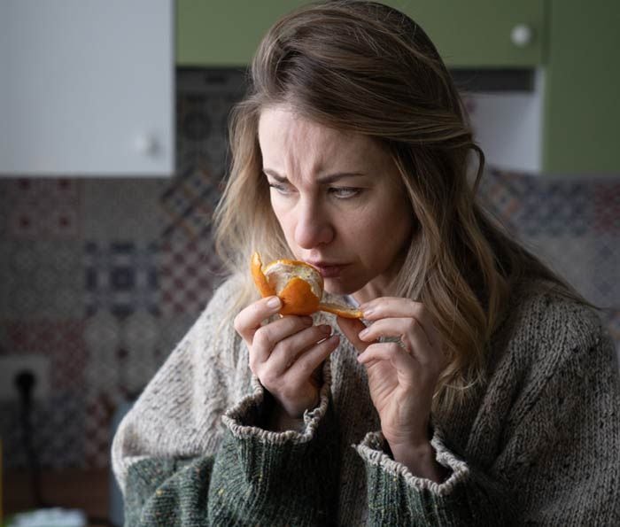 mujer oliendo una naranja