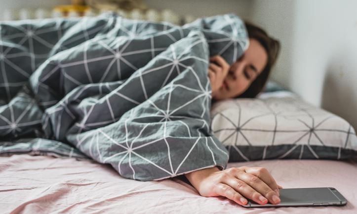 Mujer acostada tomando su celular