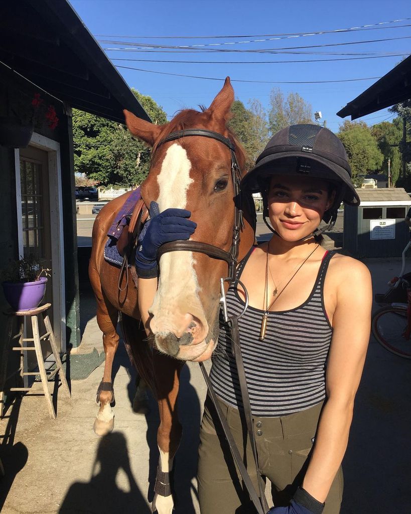 Plano medio de Chanel Maya Banks posando con un caballo