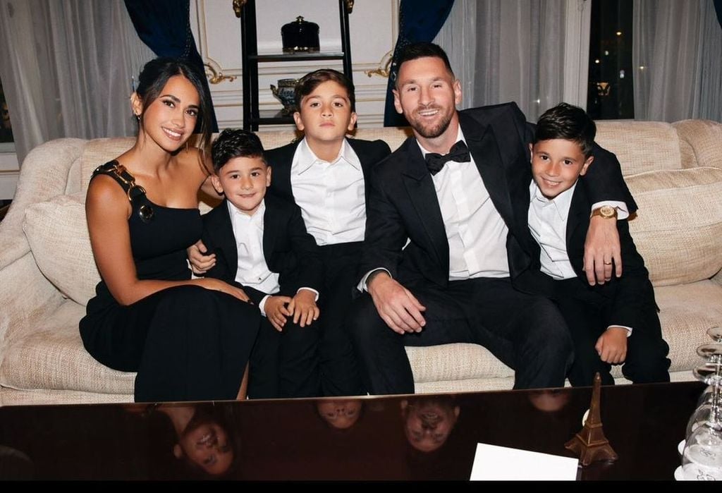 Lionel Messi con su mujer y sus hijos sentados en un sofá, vestidos de traje