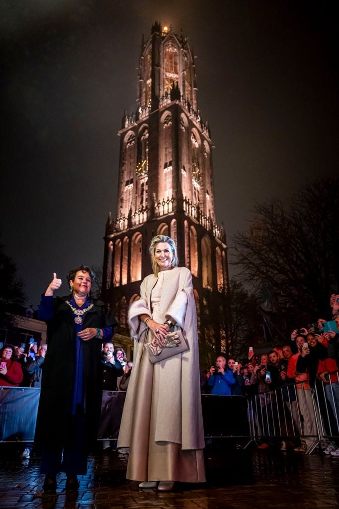 Plano entero de Máxima de Países Bajos con total look beige y la Torre Dom de fondo