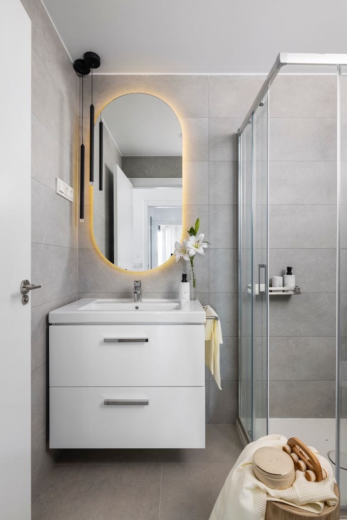 Baño gris con espejo retroiluminado