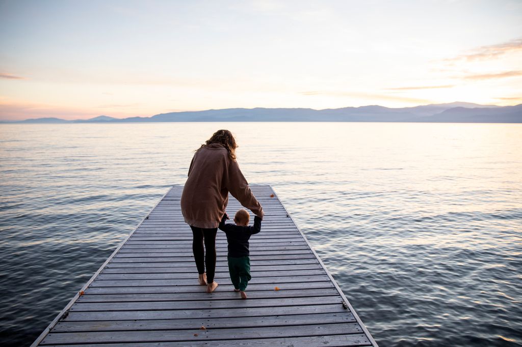 Madre con su hijo en una pasarela en la playa