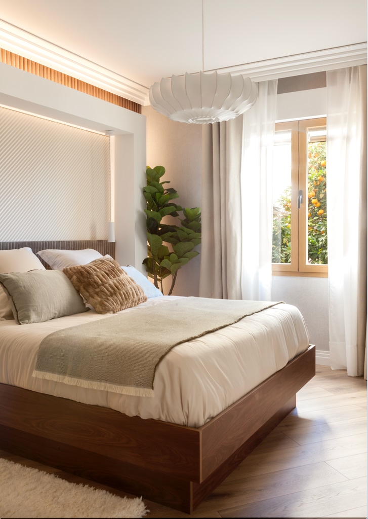 Dormitorio con suelo de madera clara y estructura de cama oscura. 