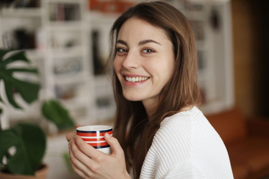 Mujer feliz tomando una infusión para los gases