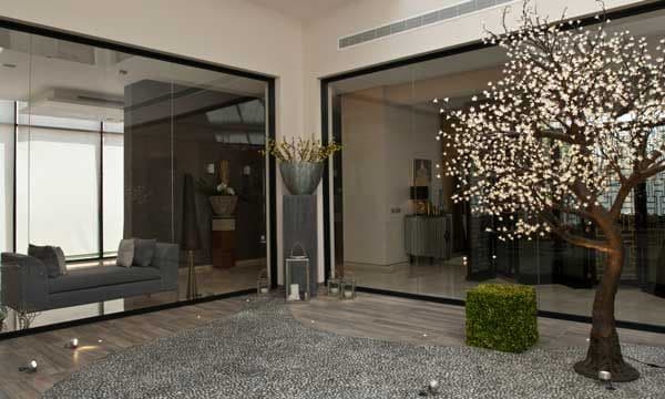 El patio central de la planta baja distribuye las diferentes áreas de esta espectacular vivienda, en una bonita y limpia geometría cúbica, gracias a las grandes cristaleras de una sola pieza, que cierran el espacio sin barreras visuales.
