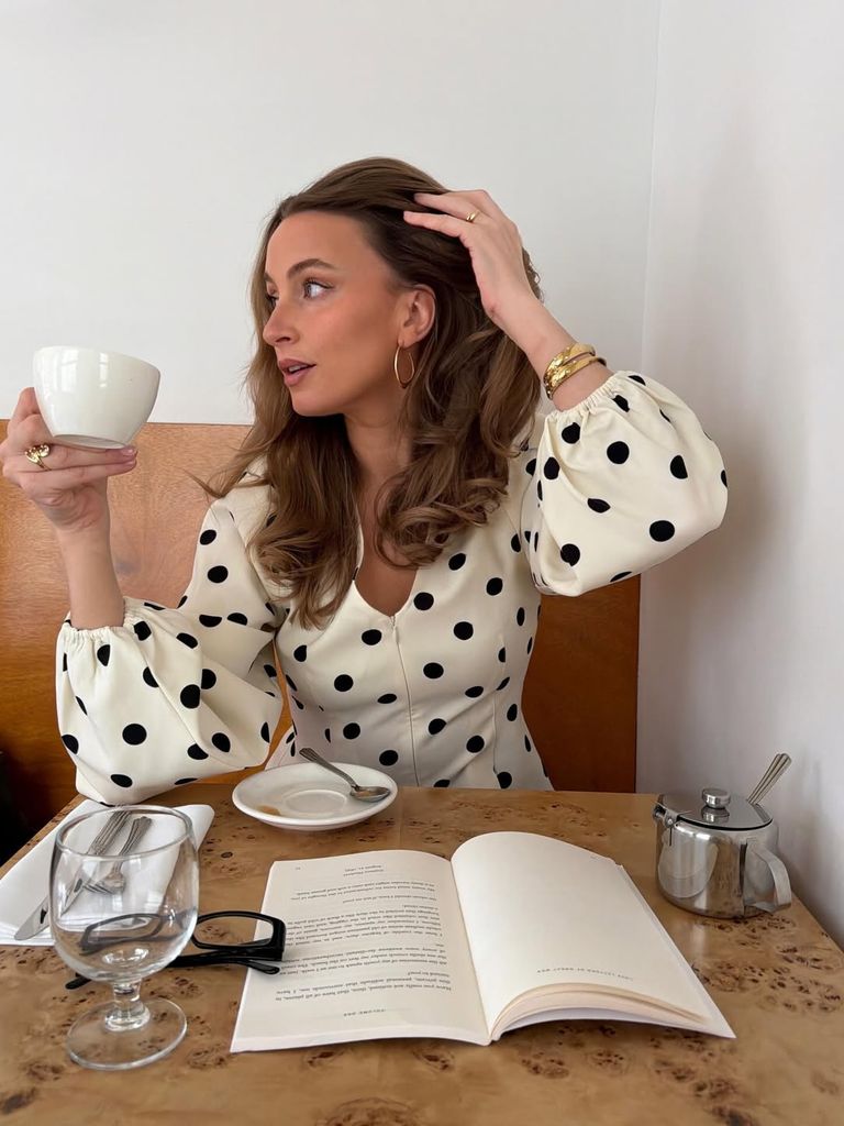Mujer con piel luminosa tomando café mientras sostiene una taza blanca.
