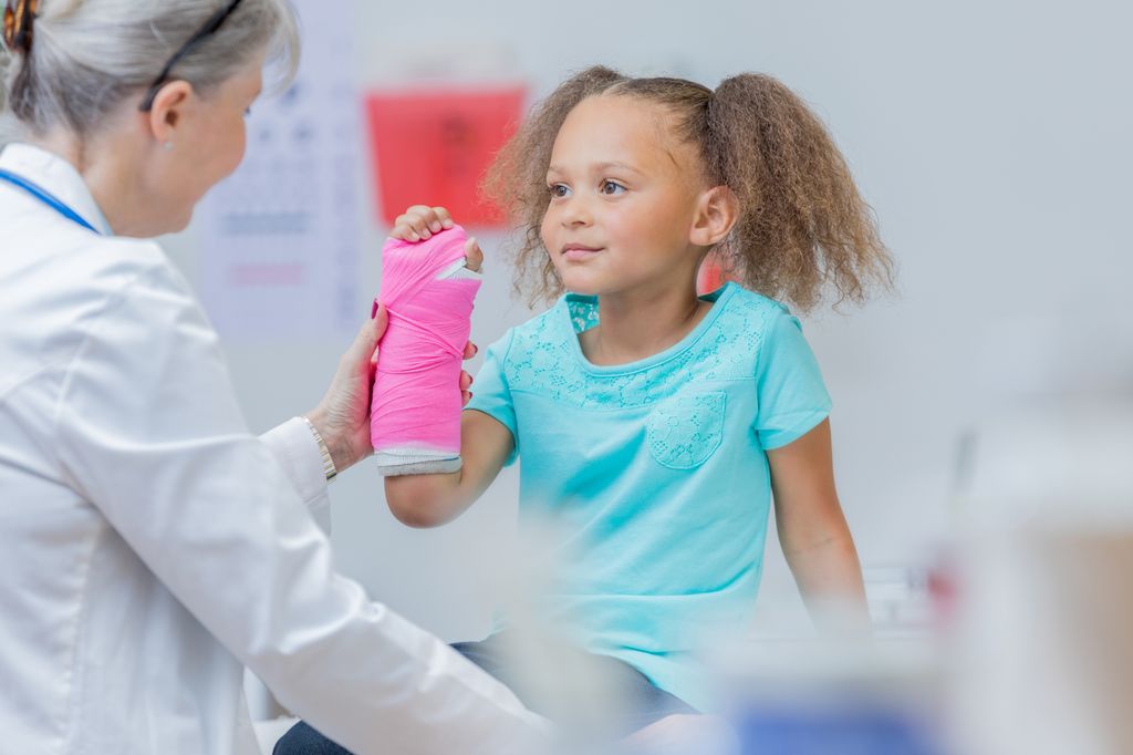 Niña con escayola en el brazo en consulta médica