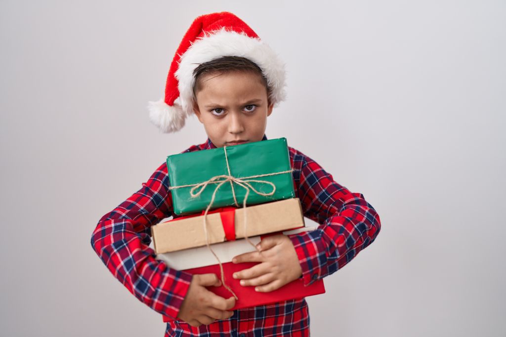 Niño con muchos regalos de Navidad con cara de enfado