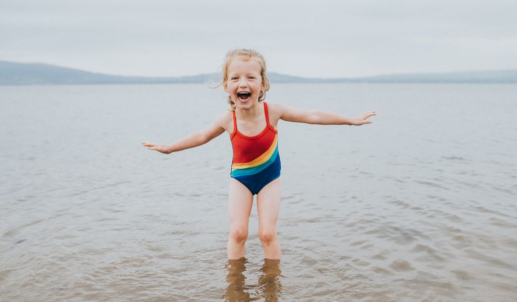niña en la playa, disfrutando del agua