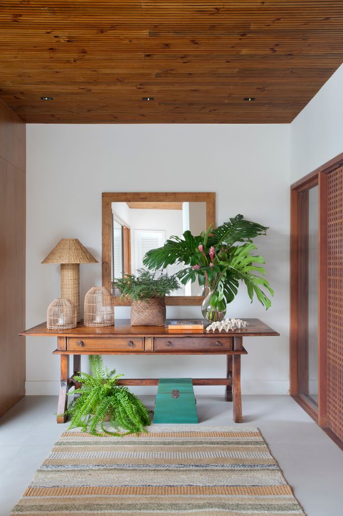 Recibidor con consola de madera, espejo y plantas