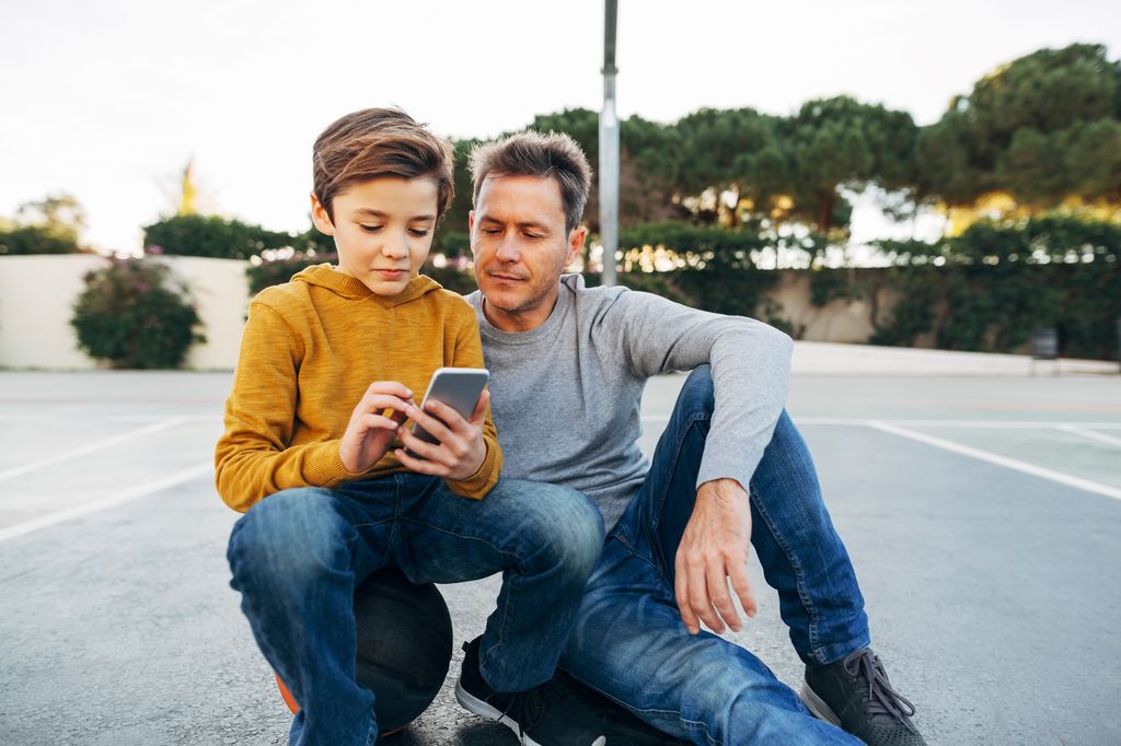 padre con su hijo mirando el teléfono móvil
