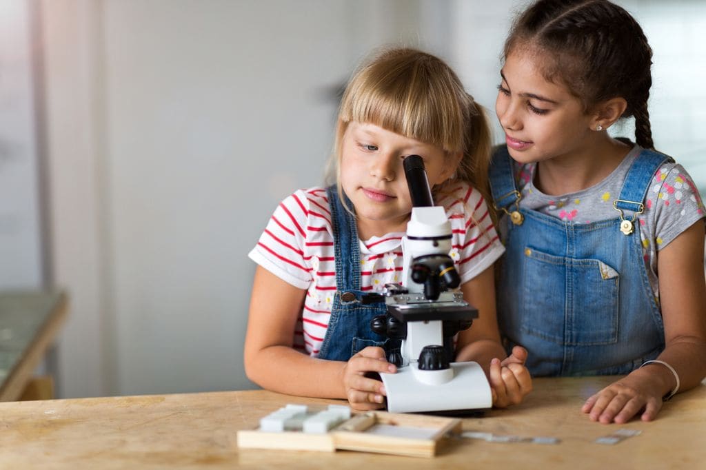 Niñas mirando por un microscopio