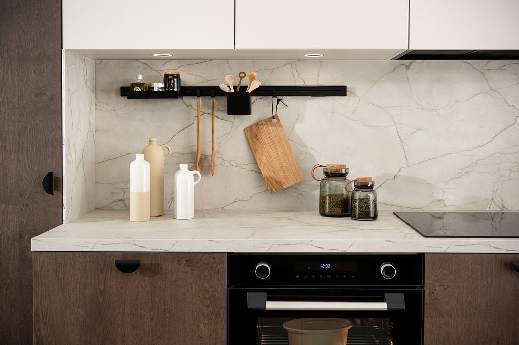 Cocina con muebles de madera y encimera y antepecho con acabado mármol. 