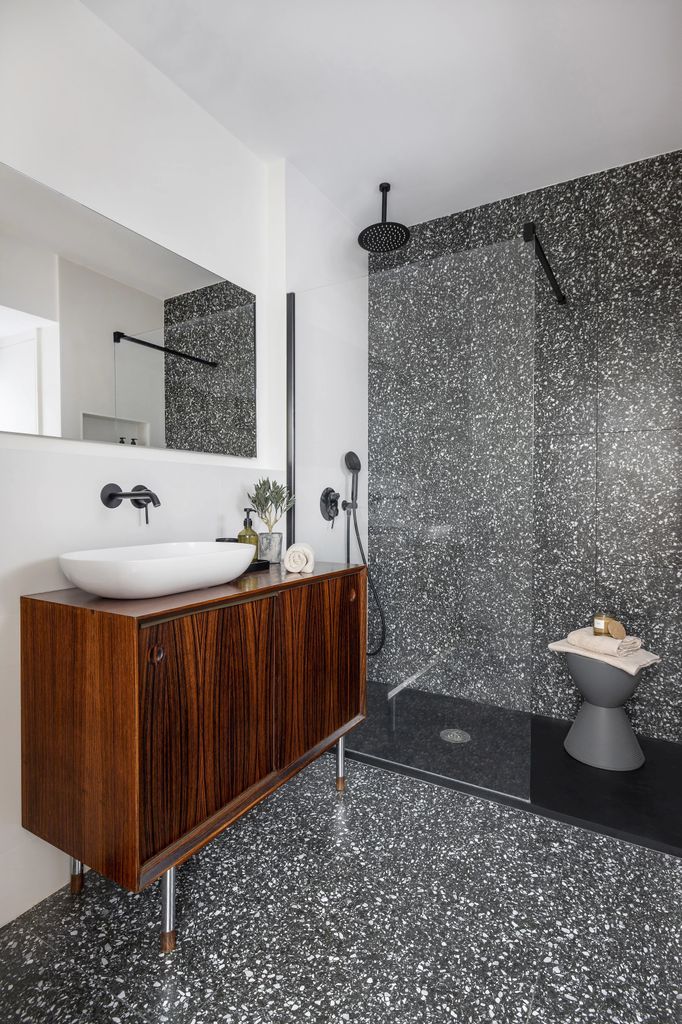Baño con mueble de madera y terrazo en suelo y pared de la ducha