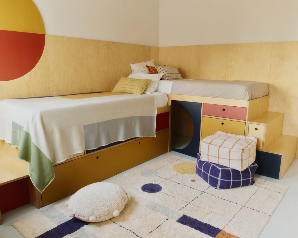 Habitación juvenil con camas en L y alfombra geométrica