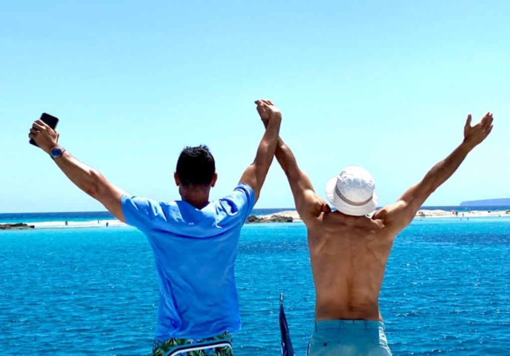 Plano medio de Jesús Vázquez con su marido Roberto Cortés con la playa de fondo