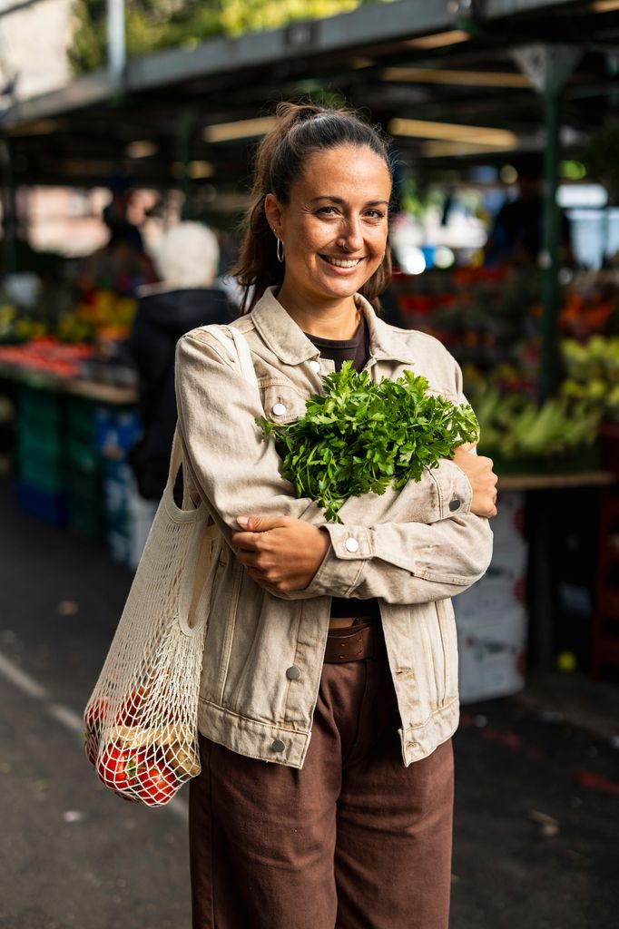 Una chica joven comprando perejil en un mercado