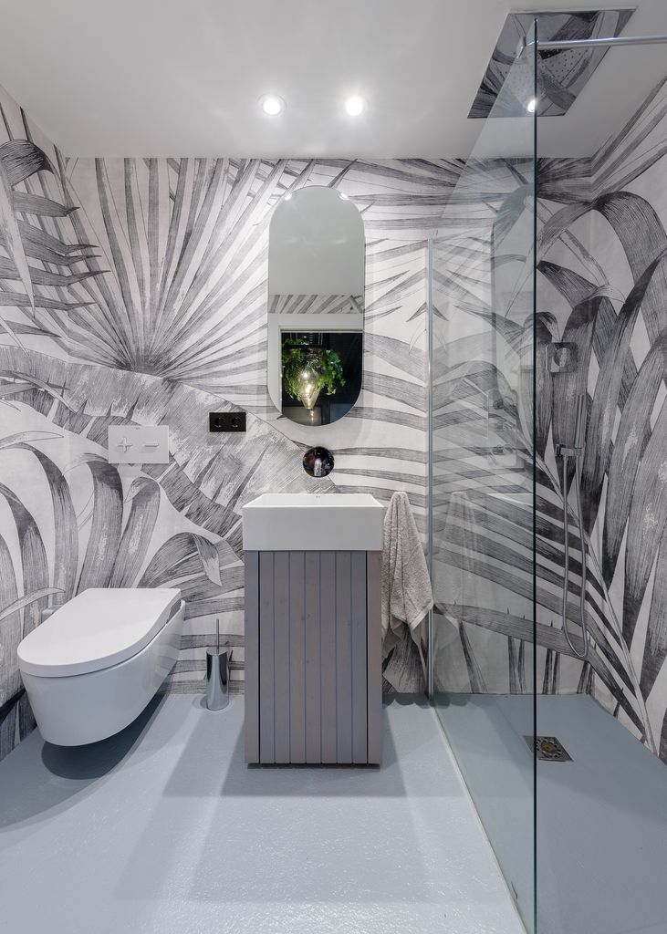 Baño pequeño con papel pintado y suelo continuo. 