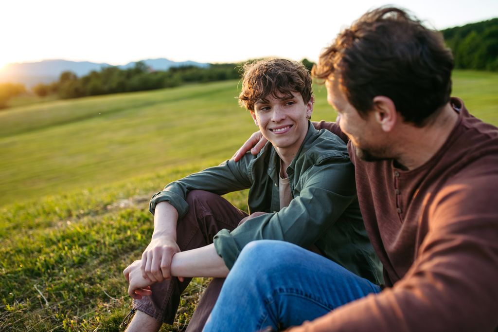 Padre hablando con su hijo adolescente en el campo