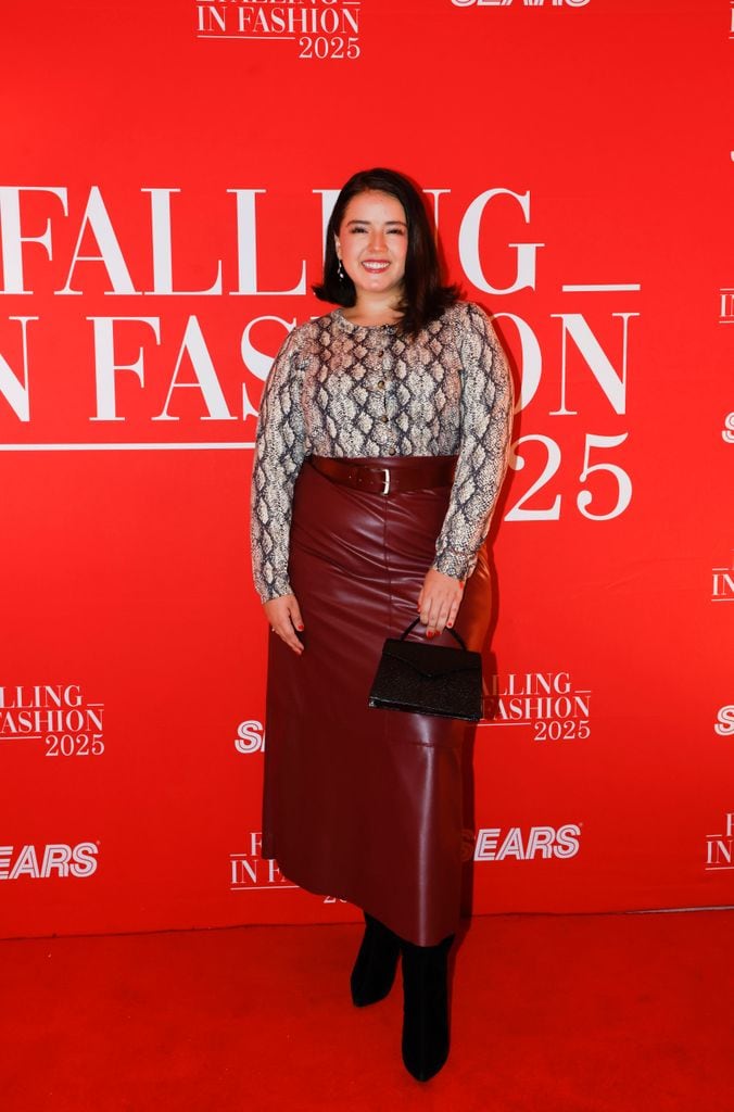 Macarena Oz luce una falda larga en color vino, botas negras, blusa animal print y bolsa de Sears