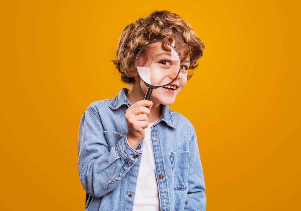 Niño con una lupa en actitud curiosa