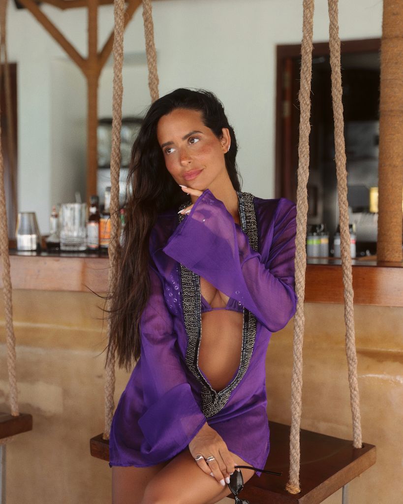 MARÍA FERNÁNDEZ-RUBÍES SOLER con vestido morado sentada en un columpio en un ambiente de verano