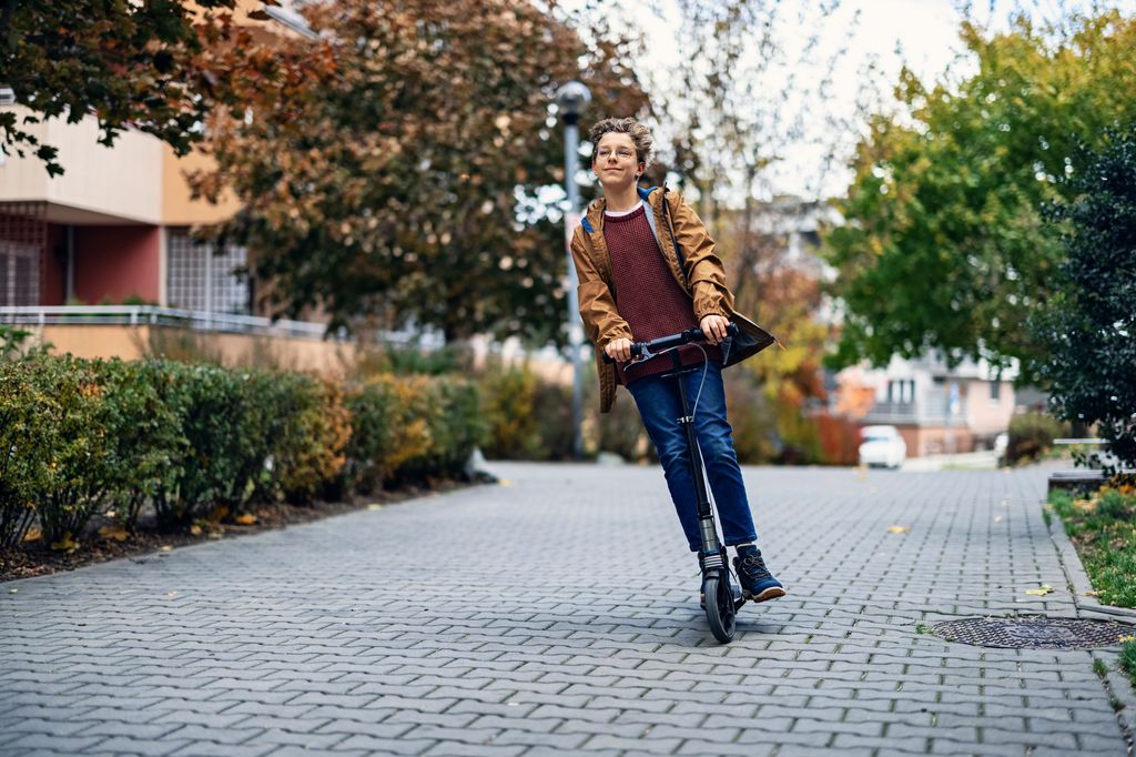 Adolescente con un patinete por la calle