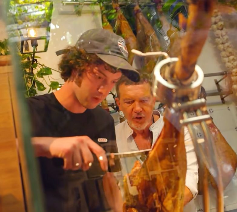 El actor malagueño muestra a su invitado cómo debe cortarse un jamón.
